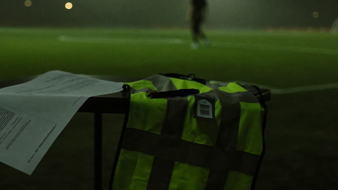 El contrato de la agencia sobre la mesa, junto al peto de entrenamiento, en el campo iluminado de noche